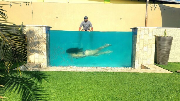 A swimming pool with a person swimming, surrounded by a stone wall and a grassy area. - Chic 1-bedroom apartment with WiFi, AC in phenomenal Tankilendert (Tankilendert)