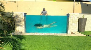 A swimming pool with a person swimming, surrounded by a stone wall and a grassy area. - Chic 1-bedroom apartment with WiFi, AC in phenomenal Tankilendert (Tankilendert)