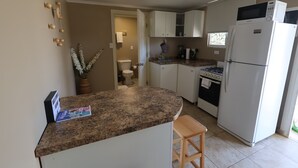 A kitchen with white cabinets, a granite countertop, a refrigerator, a stove, and a sink. - Chic 1-bedroom apartment with WiFi, AC in phenomenal Tankilendert (Tankilendert)