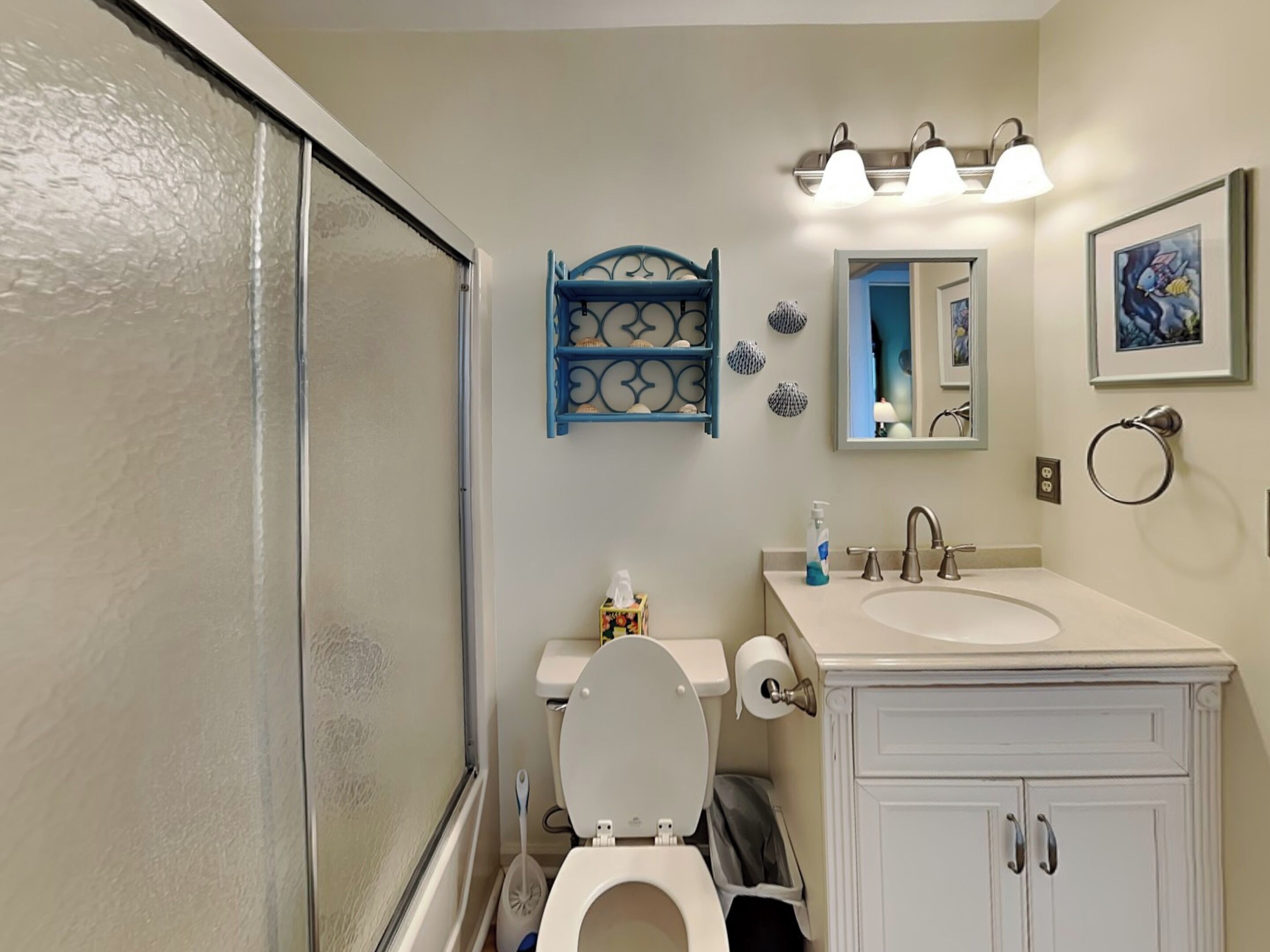A bathroom with a shower, toilet, sink, vanity, and a mirror.