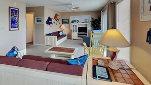 Uma sala de estar com sofá, mesa de centro, luminária e televisão.