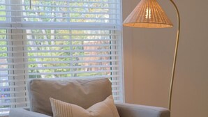 A room with a grey sofa, a round wooden table, a white candle, and a floor lamp. - Townhouse on Shipley (Cookeville)