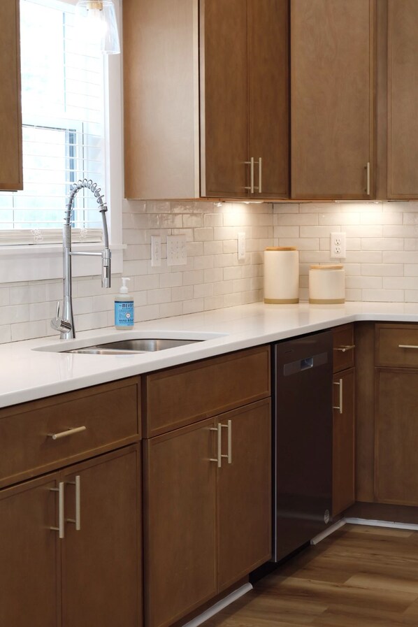 A kitchen with wooden cabinets, a stainless steel sink, and a dishwasher.