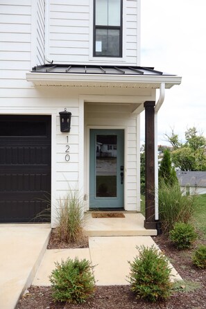 A two-story house with a black garage door, a blue front door, and a small porch with a mailbox.