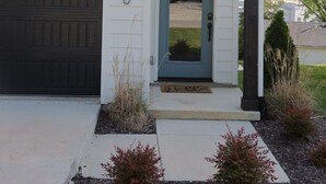 A two-story house with a dark garage door, a blue front door, and a small porch with a light fixture. - Townhouse on Shipley (Cookeville)