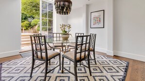 Un coin repas avec une table en verre entourée de chaises, un tapis à motifs et un luminaire suspendu.
