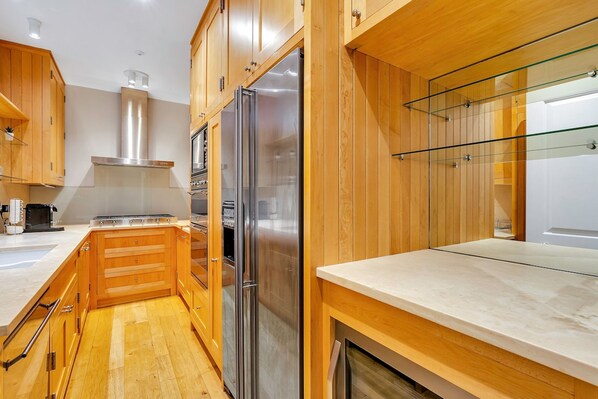 A modern kitchen with wooden cabinets, stainless steel appliances, and a glass backsplash.