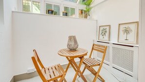 A room with a round wooden table and two chairs, a potted plant, and framed artwork on the wall. - Belgravia - Charming Spacious 4 Bed Home for 9 (London)