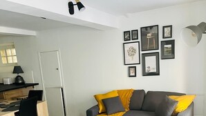 A modern living room with a grey sofa, two armchairs, a coffee table, and a dining area with a kitchen in the background.