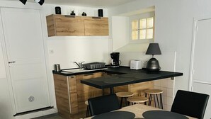 A modern kitchen with a wooden island, black chairs, and a dining table with black placemats.
