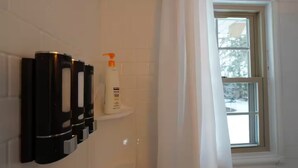 A bathroom with a white tiled wall, a shelf with toiletries, and a window with a view of trees. - Clean, Bright & Private WHOLE HOUSE 4 YOU. Safe, Centrally Located, Garage (New Britain)