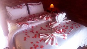 A bed with rose petals and a towel arrangement. - Cabanas Mountain (Campos do Jordão)