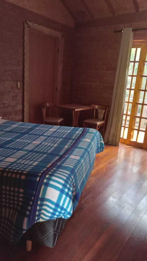 A room with a bed, a wooden table, and chairs.