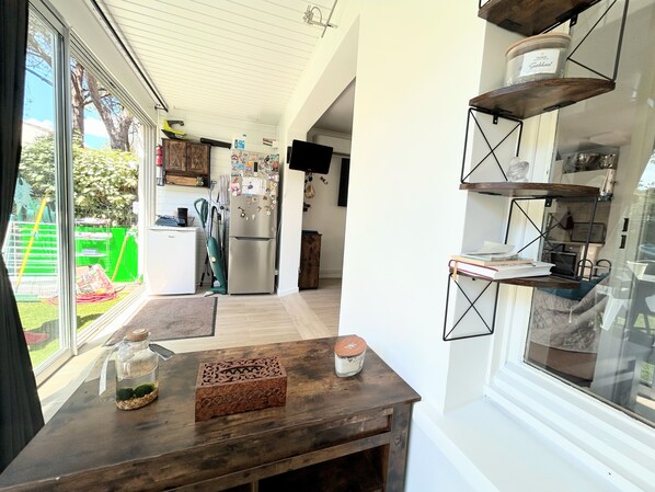 A modern kitchen with a large window, wooden table, and built-in shelves.