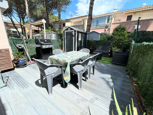 A patio with a table and chairs, a grill, and a small shed.