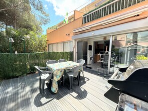 En uteplats med ett bord och stolar, en grill och en tvättmaskin i bakgrunden.