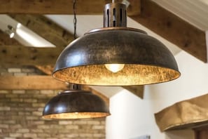 Two industrial-style pendant lights with a warm glow, hanging from a wooden ceiling with exposed beams. - Lavender - Barn Conversion - Blossom Farm (Haverfordwest)