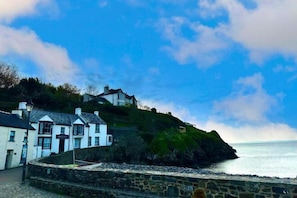 A coastal building with a stone wall, a sign reading 'WATER HOUSE,' and a view of the sea. - Lavender - Barn Conversion - Blossom Farm (Haverfordwest)