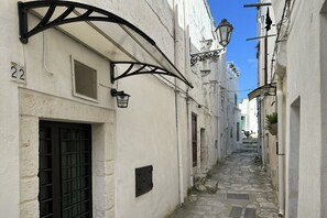 Una calle estrecha empedrada flanqueada por edificios blancos con marcos negros en ventanas y puertas.