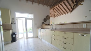 Una cocina con armarios blancos, un fregadero y un ventilador de techo.