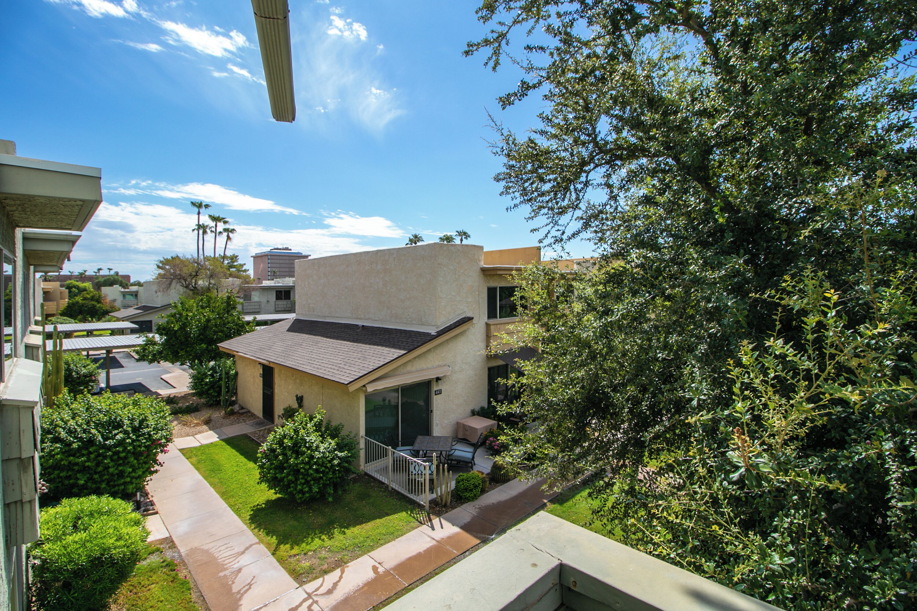 A residential area with a house featuring a patio, a small garden, and a clear blue sky.