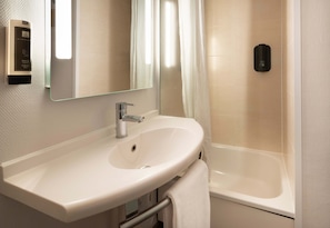 Une salle de bain avec un lavabo blanc, un miroir, un rideau de douche et une baignoire.
