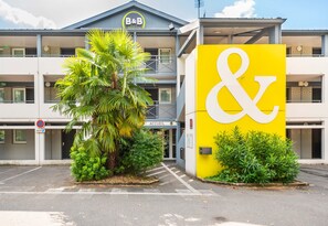 Ein Hotel mit auffälligem, gelbem Schild, doppeltem Eingang und Parkplatz.
