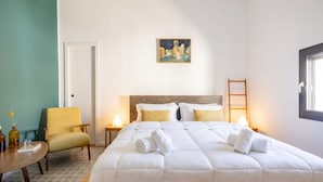 A bedroom with a large bed, a chair, a painting on the wall, and a window. - Art House with a Terrace in the Historic Center (Monopoli)