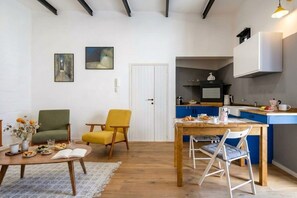 A modern living space with a dining area, kitchen, and two chairs.