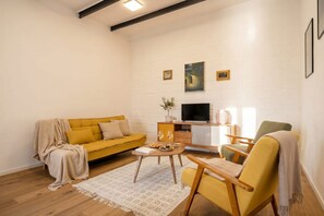 A living room with a yellow sofa, a wooden coffee table, a TV, and a fireplace. - Rare House with Terrace in the Historic Center (Monopoli)