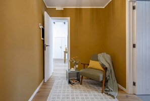 A hallway with a sofa, a small table with a vase, and a door.