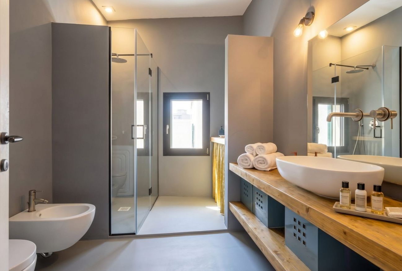 Une salle de bain moderne dotée d’une douche à parois de verre, d’un grand lavabo et d’un meuble-lavabo avec des articles de toilette.