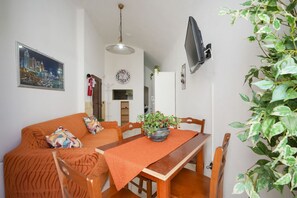 Un coin repas avec une table en bois, des chaises, une plante en pot et un tableau représentant un paysage urbain accroché au mur.