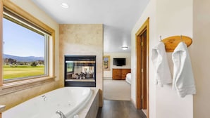 A modern bathroom with a large bathtub, a wooden vanity, and a view of a golf course. - *New Listing* 4 Bedroom House w/ Private Hot Tub (Big Sky)