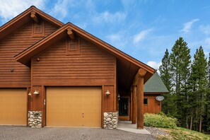 A large wooden building with a garage, stone pillars, and a satellite dish.