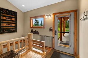 A wooden staircase leading to a door with a view of trees.