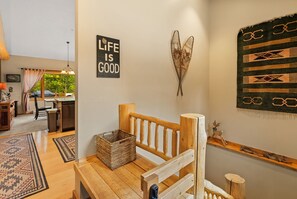 A cozy room with a wooden bench, a woven basket, and a wall with a 'Life is Good' sign.