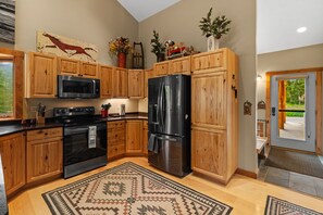 A kitchen with wooden cabinets, a black refrigerator, a microwave, and a stove.