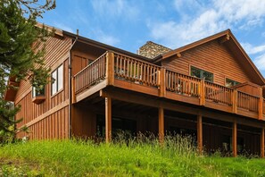 Eine Holzhütte mit Balkon, großen Fenstern und einem Steinkamin.