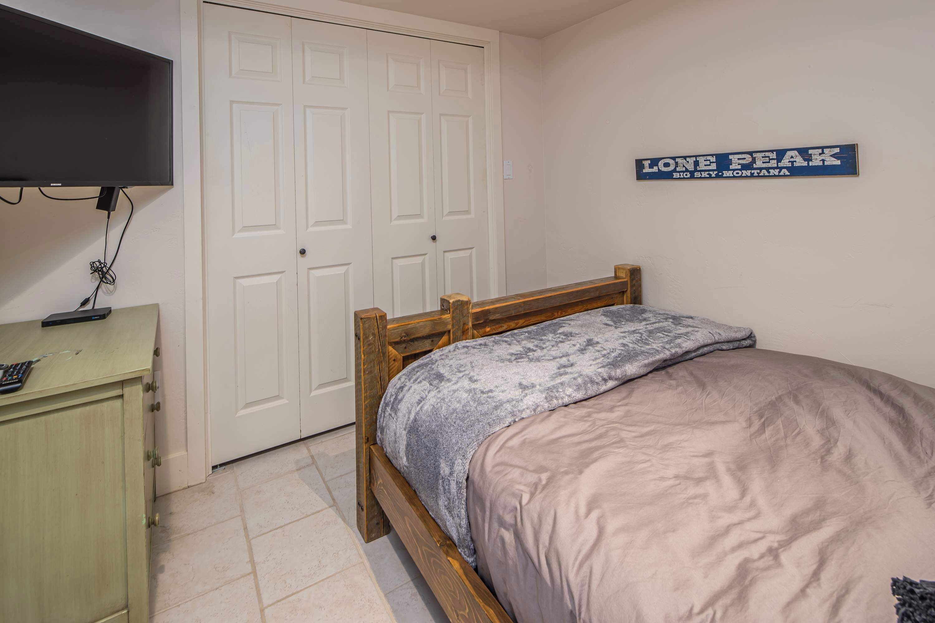 Un dormitorio con cama, cómoda, televisor y un letrero en la pared.