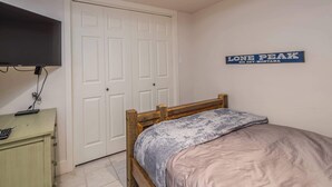 Une chambre à coucher comprenant un lit, une commode, un téléviseur et un panneau décoratif mural.