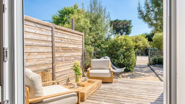 A wooden deck with outdoor furniture, a wooden fence, and greenery. - Villa Indonésie - Domaine Le Sherwood (Notre-Dame-de-Monts)