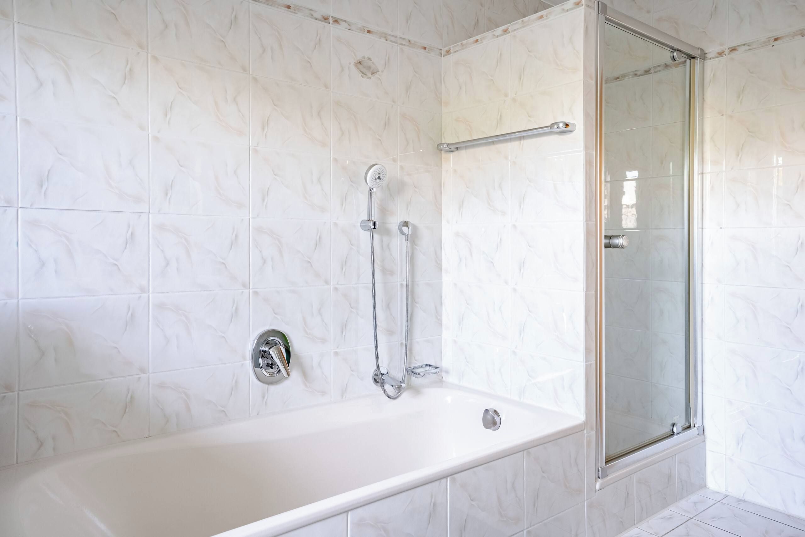Ein Badezimmer mit einer Badewanne, einer Dusche und einer gläsernen Duschkabine.