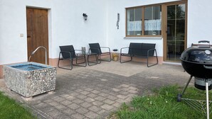 A patio with a stone water feature, outdoor seating, and a barbecue grill. - Spacious first floor apartment for the whole family near Buchenberg in Allgäu (Buchenberg)