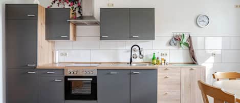 A modern kitchen with grey cabinets, a wooden countertop, a built-in oven, and a sink.