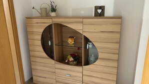 A wooden cabinet with a circular glass door, a small shelf, and a decorative item on top. - Spacious first floor apartment for the whole family near Buchenberg in Allgäu (Buchenberg)
