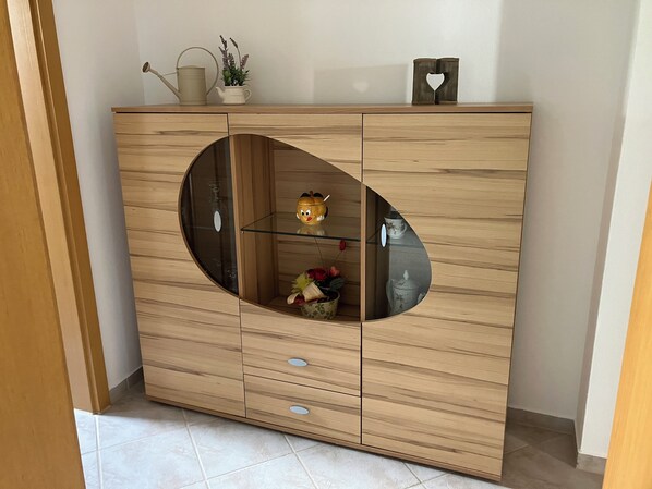 A wooden cabinet with a circular glass door, a small shelf, and a decorative item on top. - Spacious first floor apartment for the whole family near Buchenberg in Allgäu (Buchenberg)