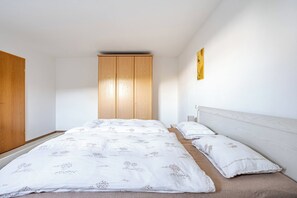 A bedroom with a bed, two bedside tables, a wardrobe, and a wall-mounted artwork. - Spacious ground-floor apartment for the whole family near Buchenberg in the Allgäu region (Buchenberg)