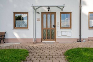 A building entrance with a numbered door, two windows, a bench, and a pathway. - Spacious ground-floor apartment for the whole family near Buchenberg in the Allgäu region (Buchenberg)
