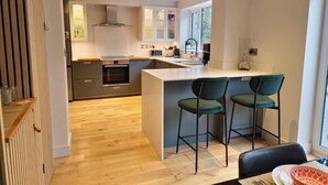 Une cuisine moderne dotée d’un îlot central, de tabourets de bar et d’un coin repas avec une table et des chaises.